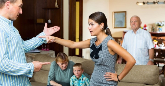 A man and woman having an argument in front of their child and the child's grandparents