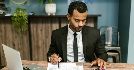 A man sitting at a desk crunching numbers on a calculator