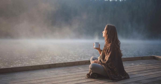 A woman holding a cup of coffee relaxing on a pier
