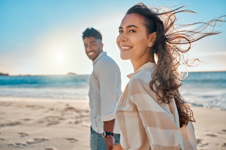 happy couple holding hands and walking along the beach