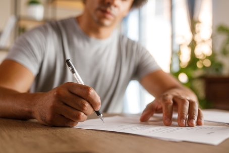 Man sitting at table, reviewing documents and signing contracts