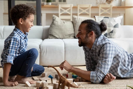 Joyful African American kid boy playing toys with father.