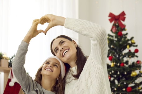 mother and daughter making heart shape with hands during the holidays