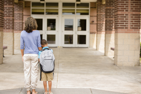 mother comforting son in front of school