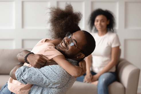 father smiling and hugging his daughter