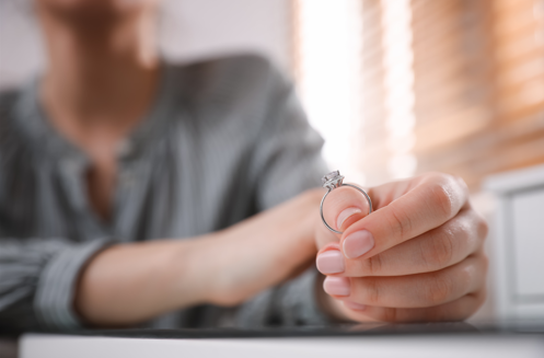 woman holding wedding ring contemplating divorce